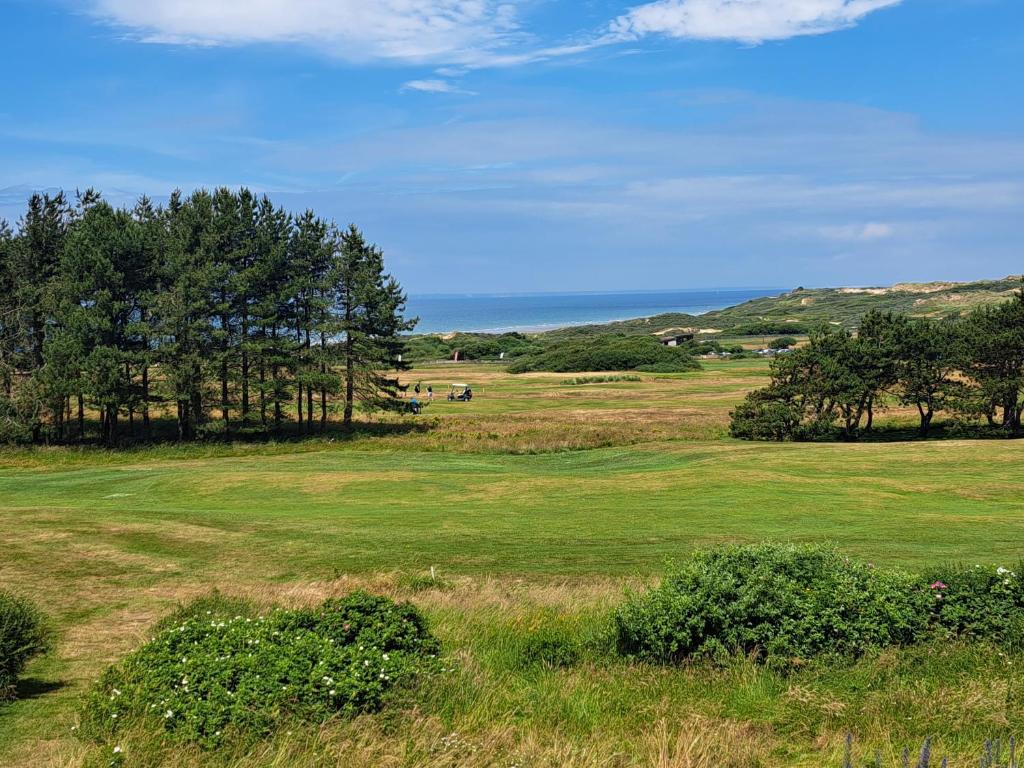 un champ d'herbe verte avec des arbres au loin dans l'établissement Happy wim', à Wimereux