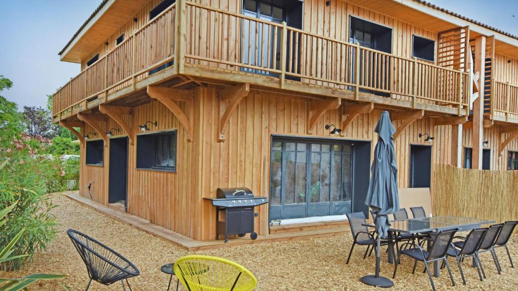 un patio avec une table et des chaises devant une maison dans l'établissement Maison 5 chambres Petit Piquey, à Lège-Cap-Ferret