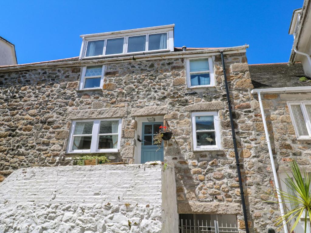 an old stone house with a blue door at Cormorant Cottage in St Ives