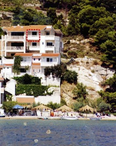 a building on a hill next to a beach with umbrellas at Villa Nada - room for 2 in Duće