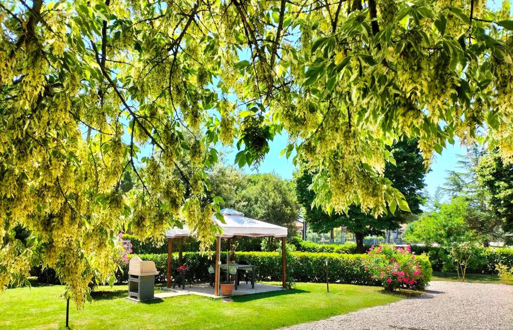 a gazebo in a park with trees and flowers at Casa vacanze Bonardini in Castiglione del Lago