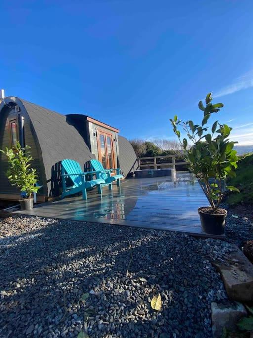 a house with chairs and a pond in front of it at Ocean View with hot tub in Barmouth