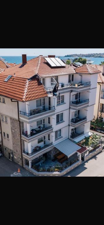 a large white building with a red tile roof at Milchevi Guesthouse in Sozopol