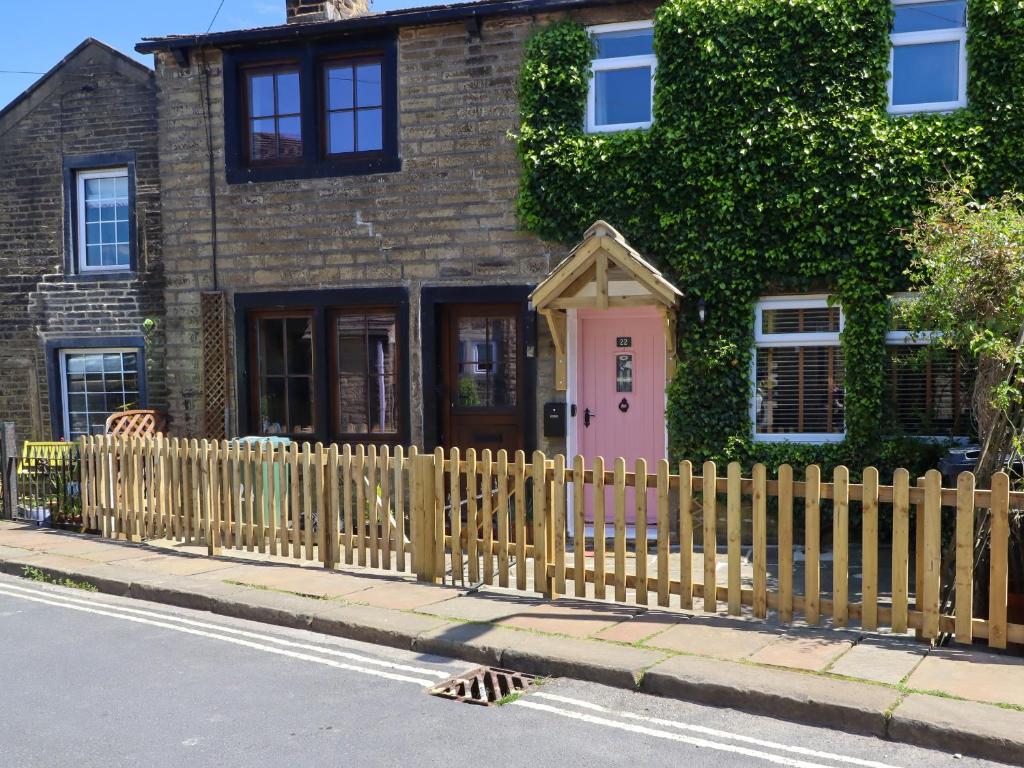 a wooden fence in front of a house with a pink door at Emily Cottage in Keighley