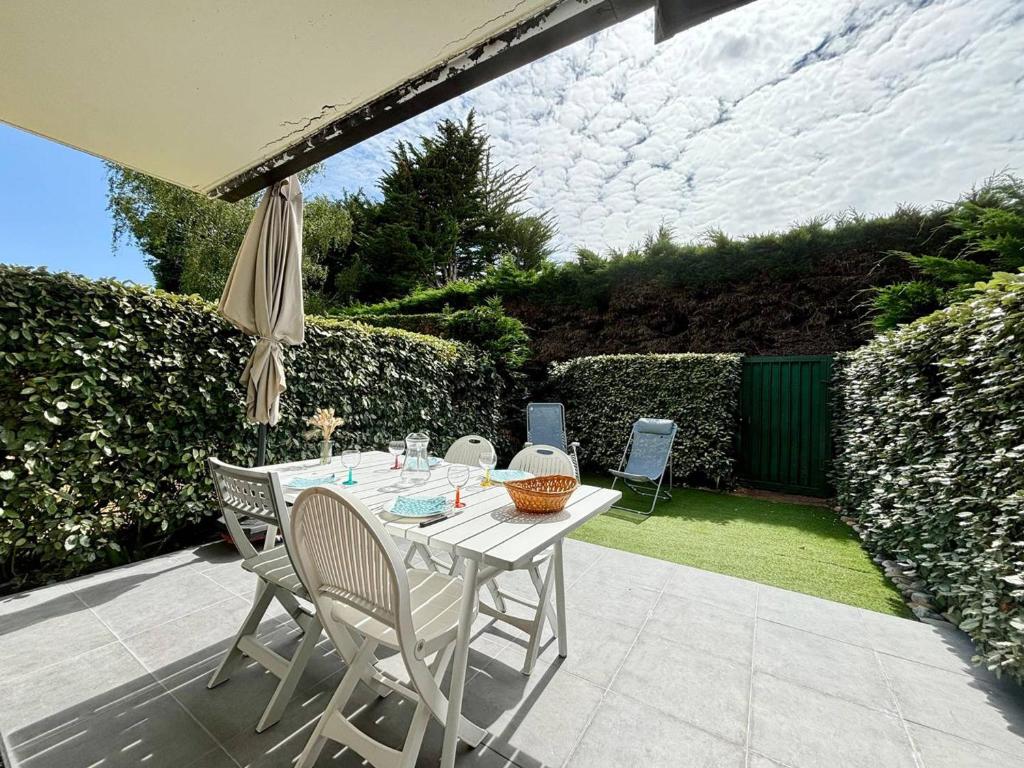 une table avec des chaises et un parasol sur une terrasse dans l'établissement Appartement 2 pièces avec jardin, proche plage de Beaumer, Carnac - 4 pers. - FR-1-377-19, à Carnac