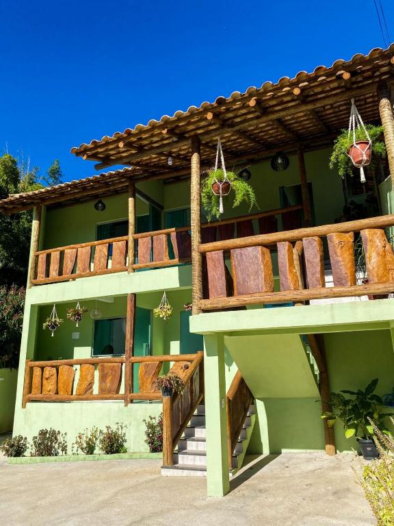 a green house with a wooden balcony and stairs at Pousada Cardeal Mota in Serra do Cipo