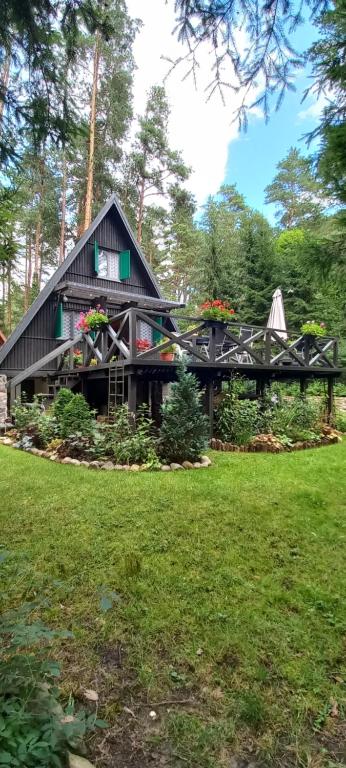 ein Haus mit einem schwarzen Dach mit Blumen darauf in der Unterkunft Domek letniskowy nad jeziorem, Mazury in Teerau