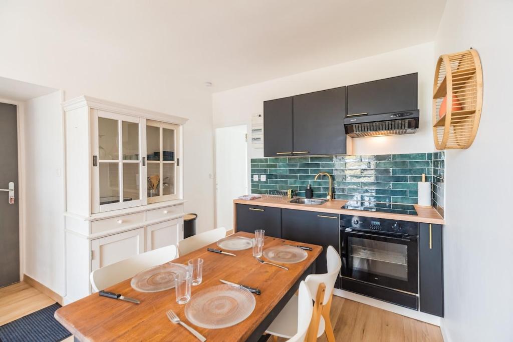 una cucina con tavolo in legno e piatti di Evasion Paimpol appartement neuf et confortable a Paimpol