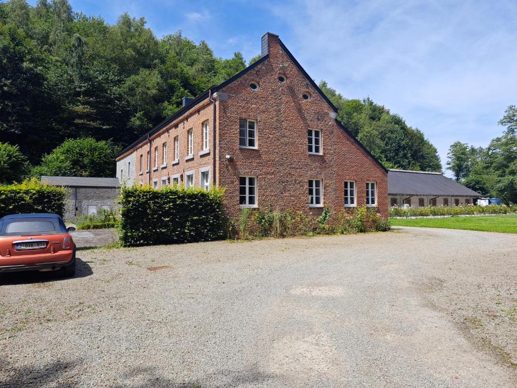 an old brick building with a car parked in front at Harmonie et les fées du Flavion - chambres in Onhaye