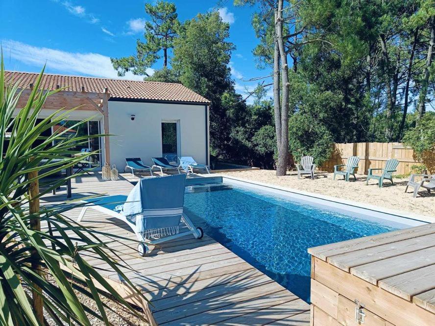 une piscine avec des chaises et une maison dans l'établissement MAISON 4 CHAMBRES PISCINE CHENAL DES DUNES, à Saint-Jean-de-Monts