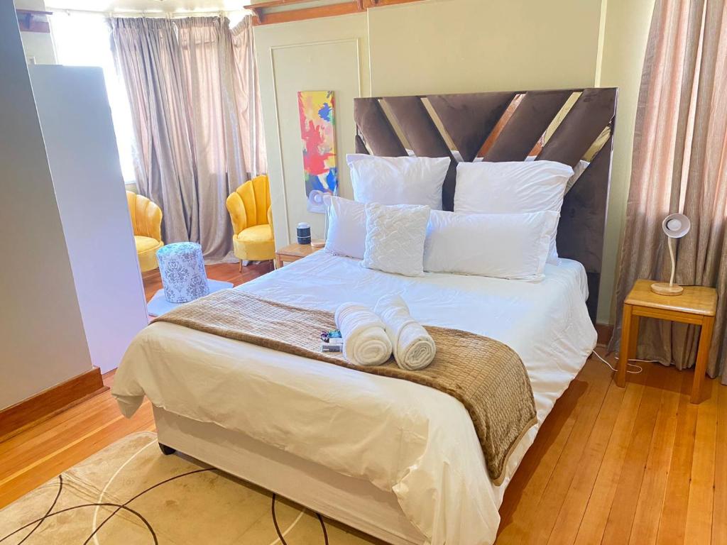 a bedroom with a large bed with white pillows at Grace on 51York Lodge in Johannesburg