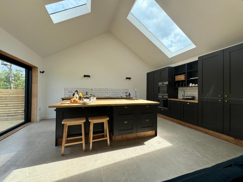 a kitchen with black cabinets and a kitchen island with skylights at Threshing Barn- Modern 5 Bed, 10 person, Barn Conversion in a Rural Location with Great Access in Silkstone