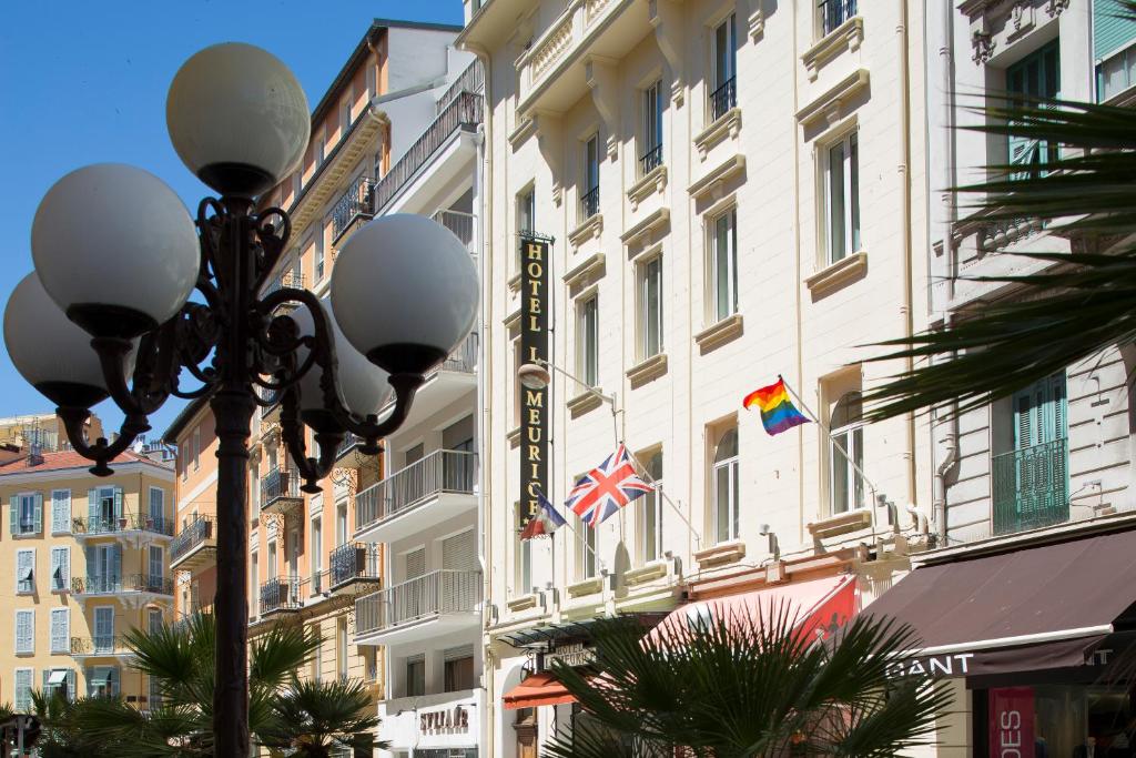 una luz de la calle frente a un edificio con banderas en Hotel Le Meurice, en Niza