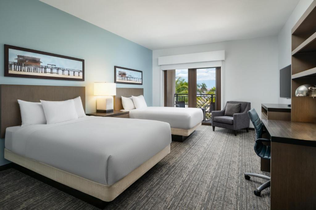 a hotel room with two beds and a desk at Hyatt House Naples 5th Avenue in Naples
