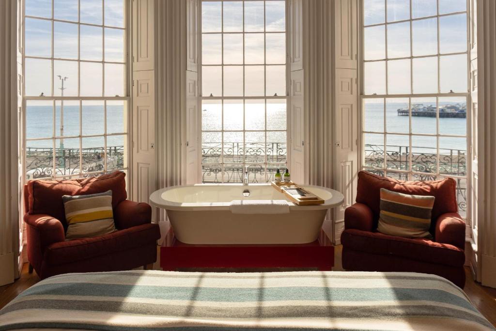 a bedroom with a tub and two chairs in front of windows at Drakes Hotel in Brighton & Hove