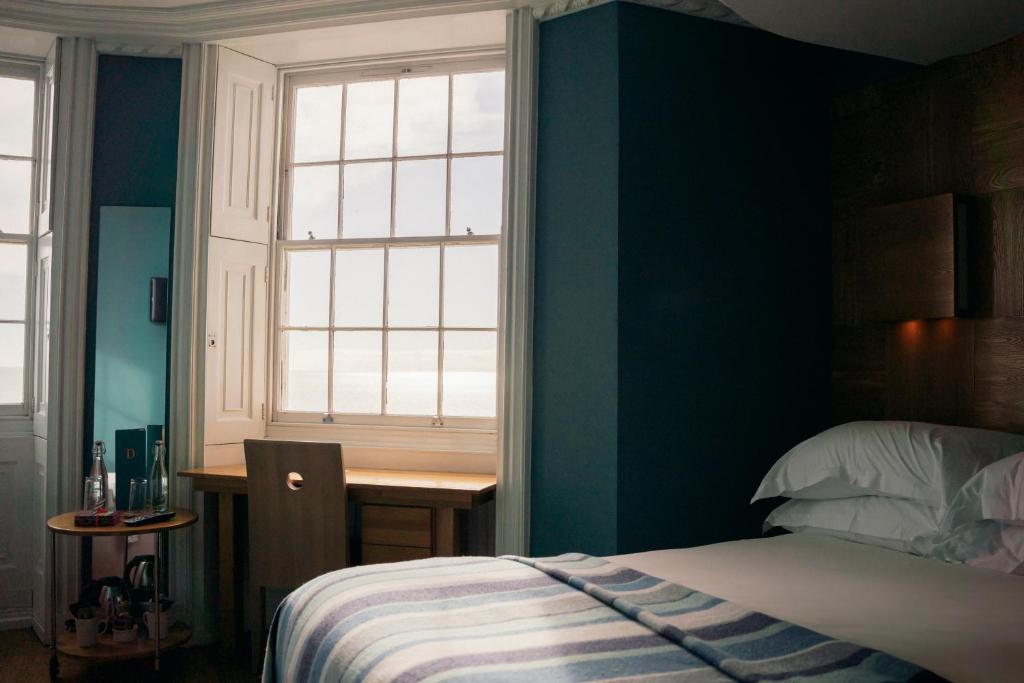 a bedroom with a bed and a desk and a window at Drakes Hotel in Brighton & Hove