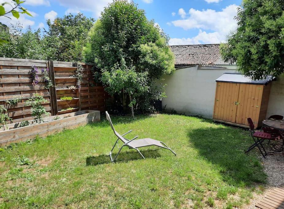 une chaise assise dans l'herbe dans une cour dans l'établissement Maison Poitiers 3 chambres à 15 min Futuroscope, à Poitiers
