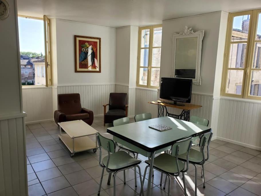 un salon avec une table, des chaises et une télévision dans l'établissement Chez Anne-Laure, à Villeneuve-sur-Lot