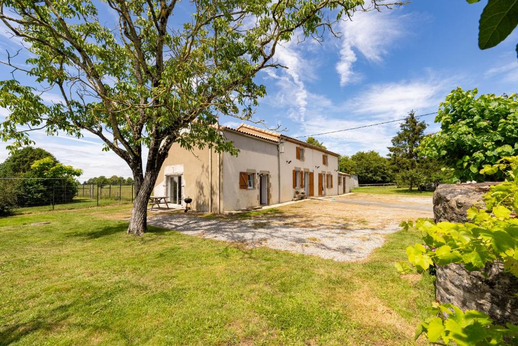 une vieille maison avec un arbre dans la cour dans l'établissement Gîte La Clé des Champs, à Saint-Étienne-du-Bois