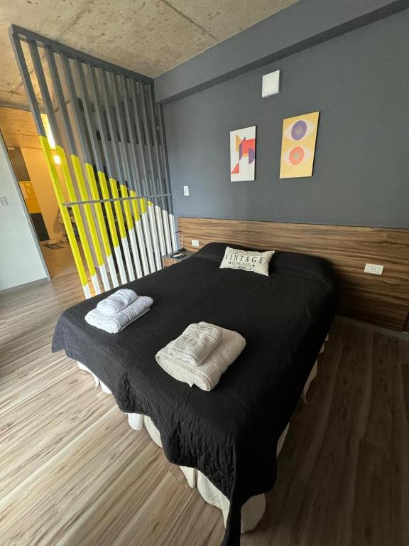 a bedroom with a black bed with two pillows on it at BEM Apartamento in Salta