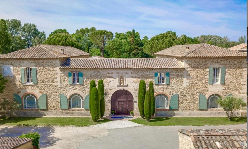une grande maison en pierre avec des cyprès devant dans l'établissement Provence Monastery, à Althen-des-Paluds