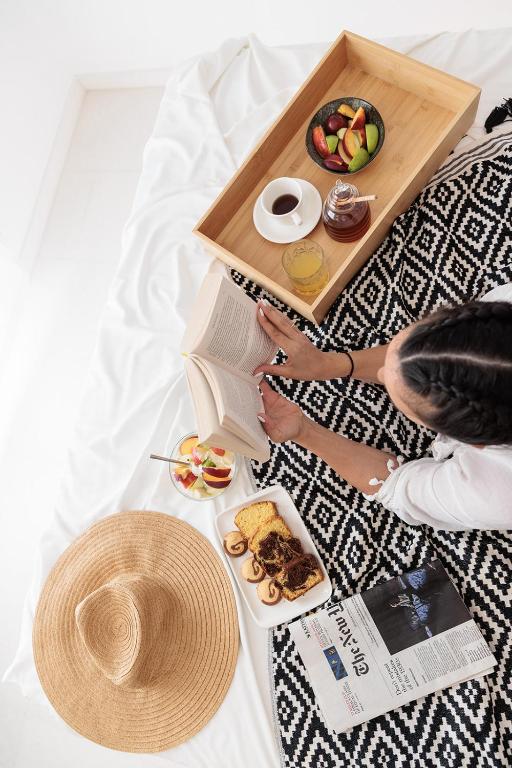 a person sitting on a bed with a tray of food at Naxos Earth Suites in Mikri Vigla