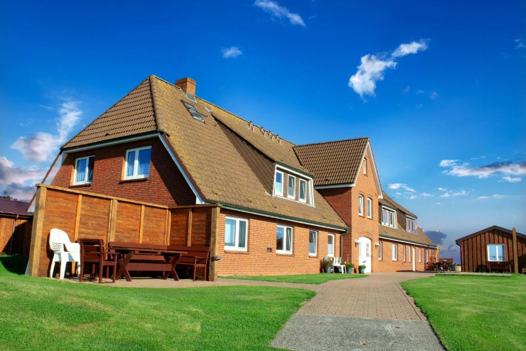 a large house with a table in front of it at Gästehaus Bi de Ley in Langeneß