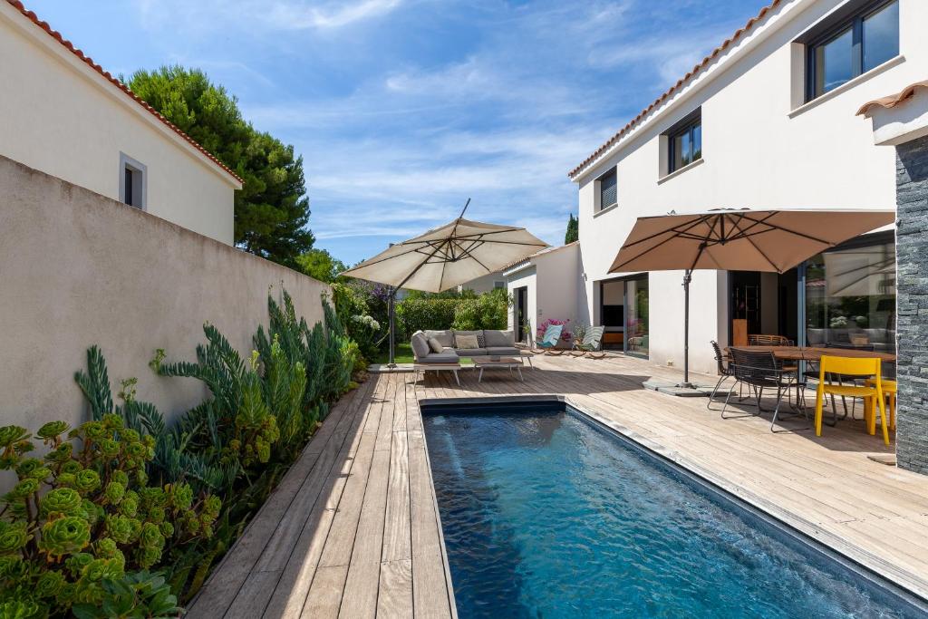 une maison avec une piscine et une terrasse avec des parasols dans l'établissement Villa avec piscine à Marseille, à Marseille