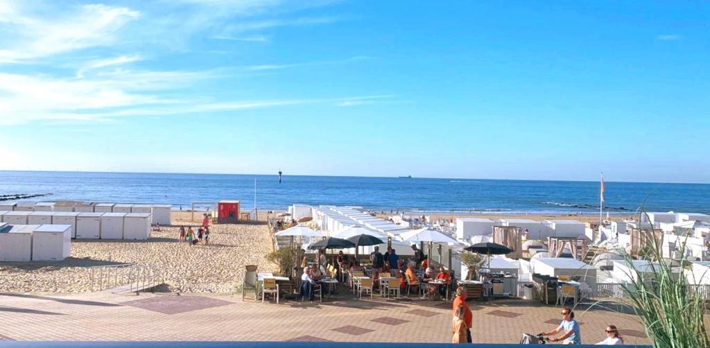 ein Strand mit weißen Sonnenschirmen und Menschen am Strand in der Unterkunft Superbe appartement digue vue mer in Knokke-Heist