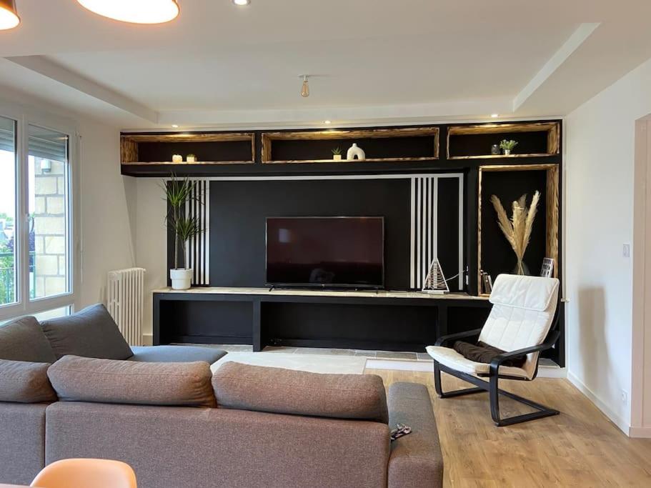 un salon avec un canapé et une télévision à écran plat dans l'établissement Appartement cosy - Le Verdun, à Caen