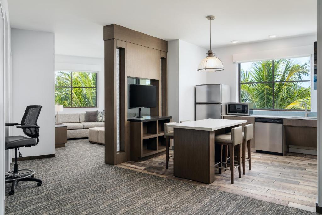 an open kitchen and living room with a table and chairs at Hyatt House Naples 5th Avenue in Naples