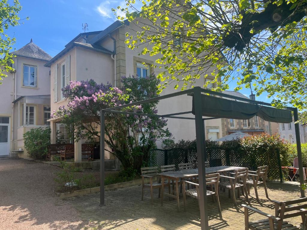 une table et des chaises sous un parasol devant un bâtiment dans l'établissement Aux Roses, à Saint-Honoré-les-Bains
