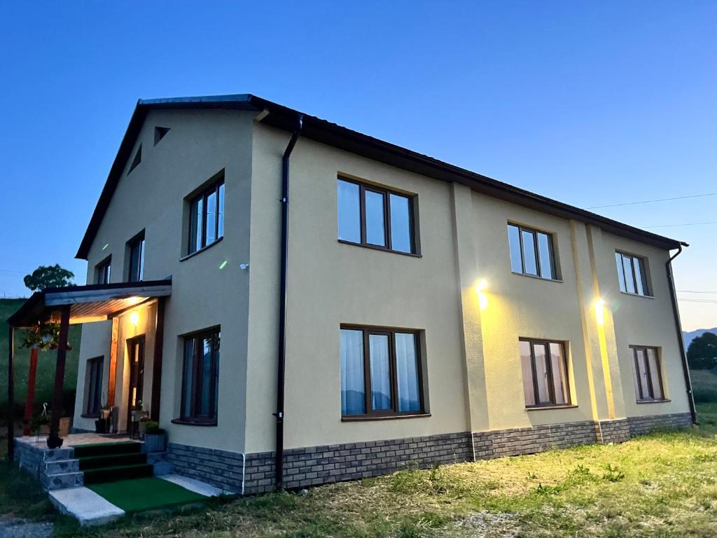 a large white house with the lights on at Casa Liniștea Munților in Fundata