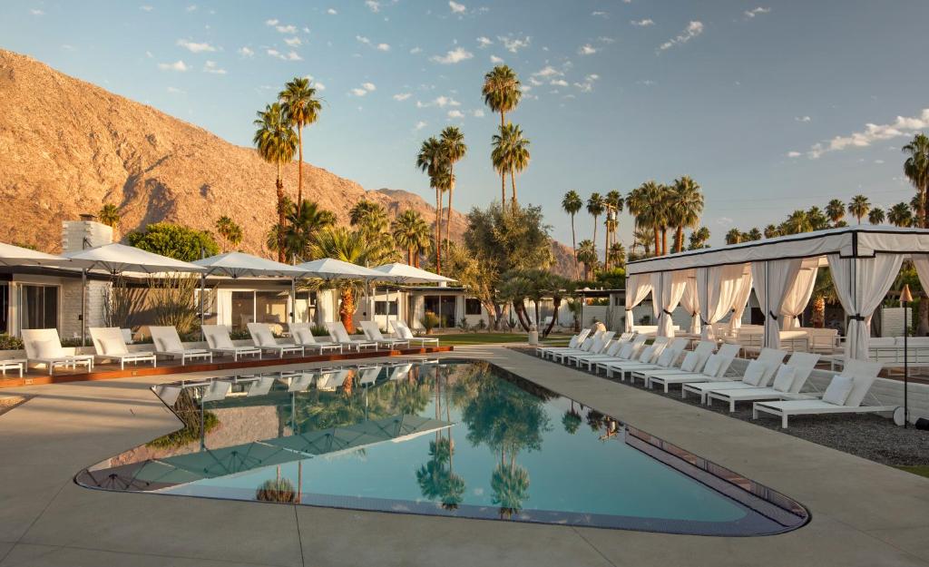 una piscina resort con sillas blancas y palmeras en L'Horizon Resort & Spa, Hermann Bungalows, en Palm Springs
