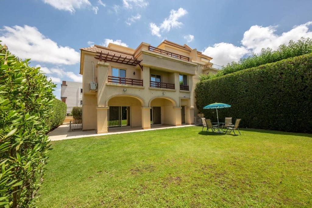 une maison avec une cour dotée de chaises et d'un parasol dans l'établissement Rihana Villa studios, à Borg El Arab