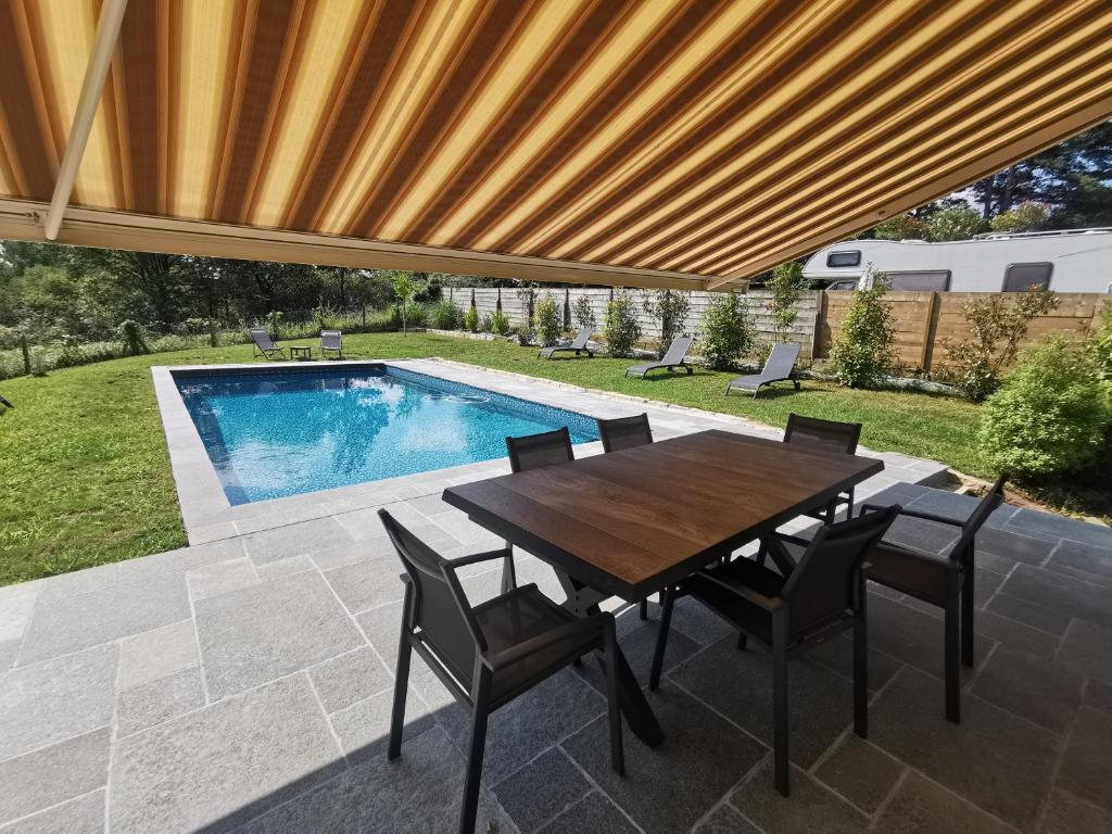 un patio avec une table et des chaises et une piscine dans l'établissement Fleurs, à Bassussarry