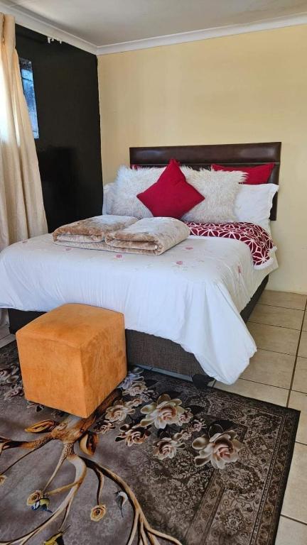 a bedroom with a bed with red and white pillows at Goodlife guest house in klerksdorp in Klerksdorp