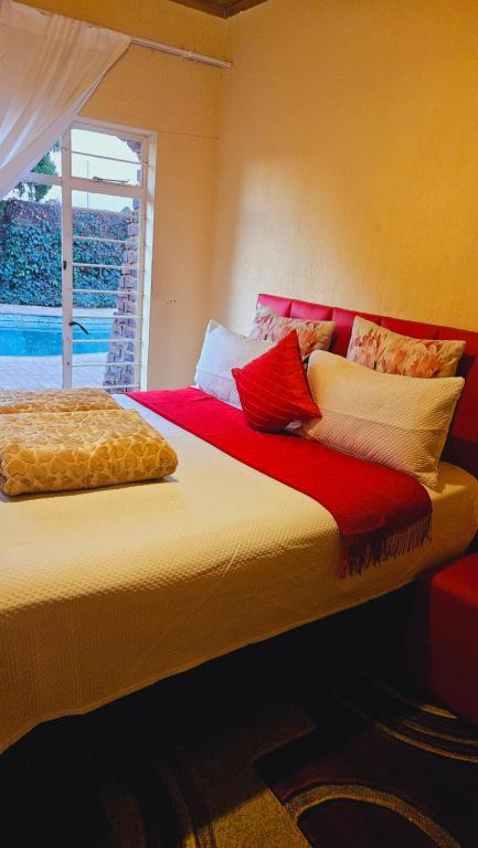 a bedroom with a large bed with red and white pillows at Goodlife guest house in klerksdorp in Klerksdorp