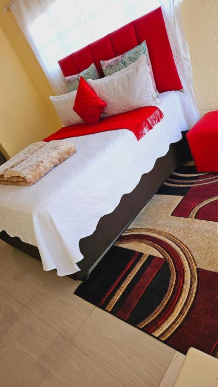 a bedroom with a large bed with red and white pillows at Goodlife guest house in klerksdorp in Klerksdorp