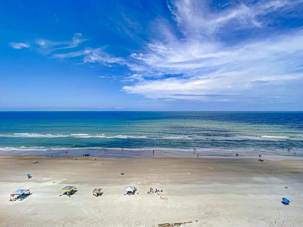 a beach with people and umbrellas on the sand at Penthouse Condo with wrap around views of the ocean - SR802 in Edgewater