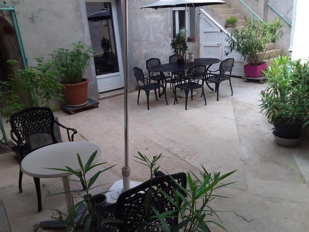 een terras met een tafel, stoelen en een parasol bij Au Terminus 6 Personnes in Hautvillers