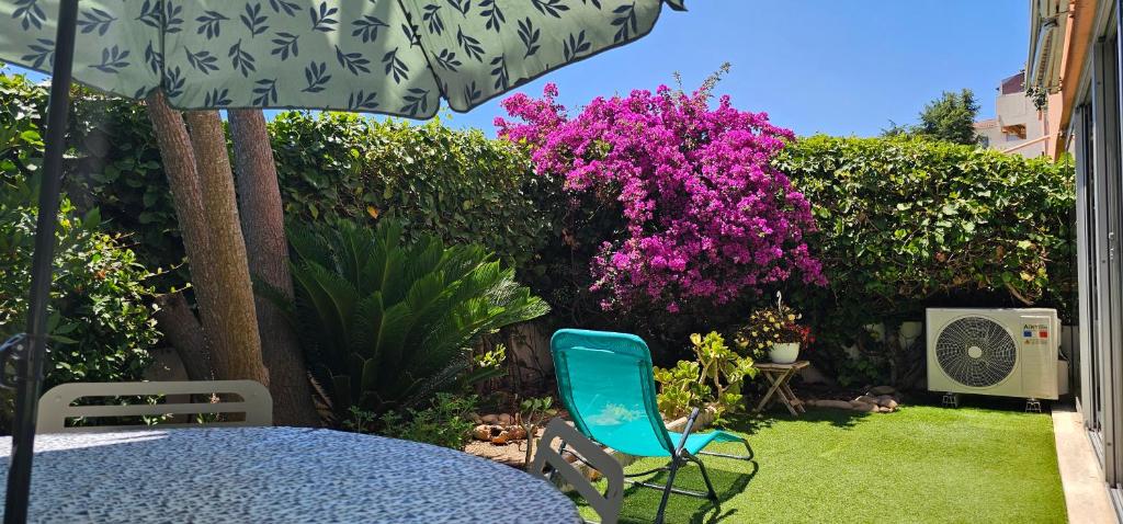 une terrasse avec une table, des chaises et des fleurs violettes dans l'établissement Grand T2 60M² /Jardin 50M² plein sud /Mer à pieds, à Saint-Mandrier-sur-Mer