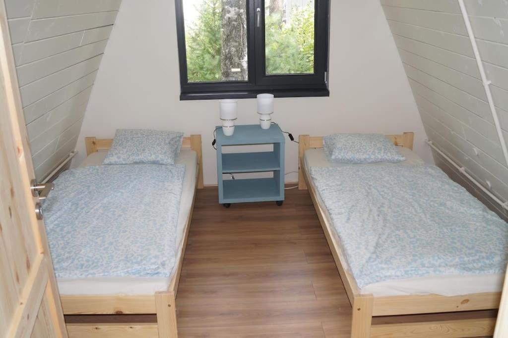 two beds in a room with a table and two windows at Domek nad Jeziorem Kaszuby max 6 os in Bieszkowice