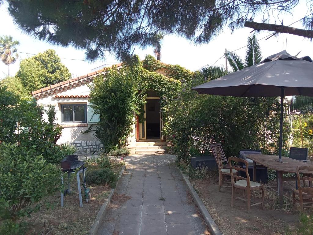 une maison avec un parasol, une table et des chaises dans l'établissement Le Mazet, chambre chez l'habitant, à Cagnes-sur-Mer