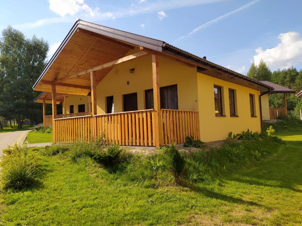 a yellow house with a wooden fence in a yard at Domki Letniskowe Cyprys in Chańcza