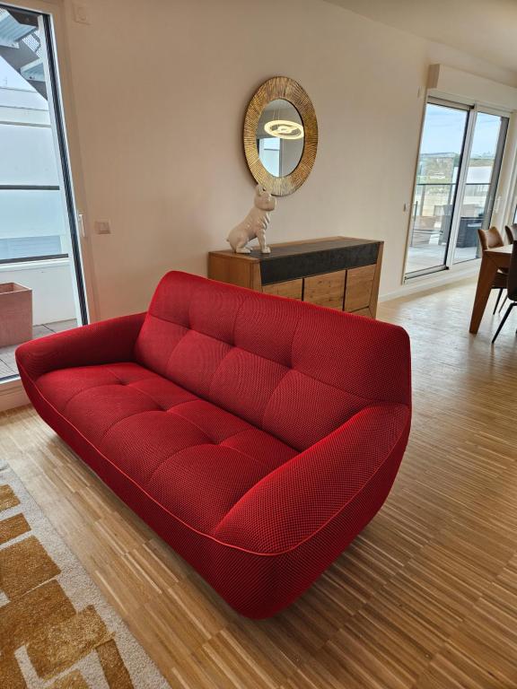 a red couch in a living room with a mirror at Appartement neuf en duplex in Saint-Maur-des-Fossés