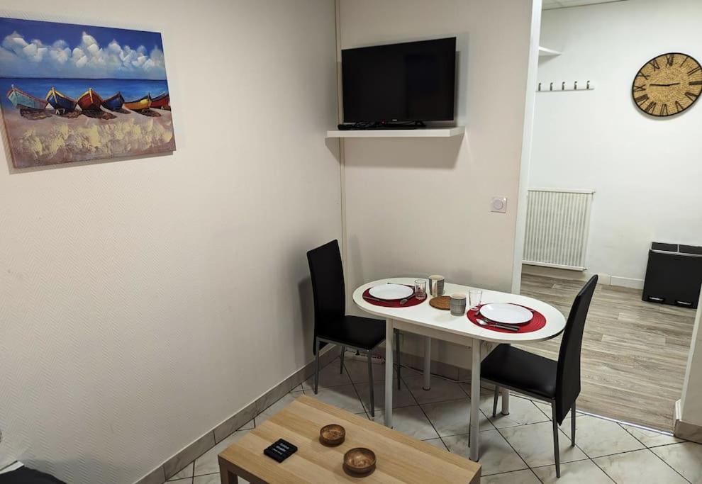 une chambre avec une table, des chaises et une horloge dans l'établissement Paisible - Proche Palais des Sports et Zénith, à Caen