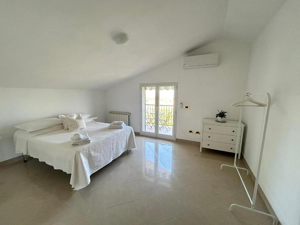 a white bedroom with a bed and a dresser and a window at Casa vacanze Villa Raffaella in Lanciano
