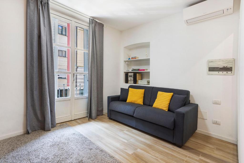 a living room with a blue couch with yellow pillows at Porta Venezia Comfortable Apartment in Milan