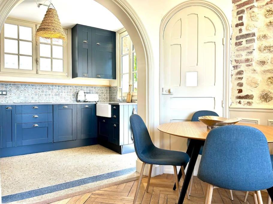 a kitchen with blue cabinets and a table and chairs at Villa Marengo, jardin privatif in Trouville-sur-Mer